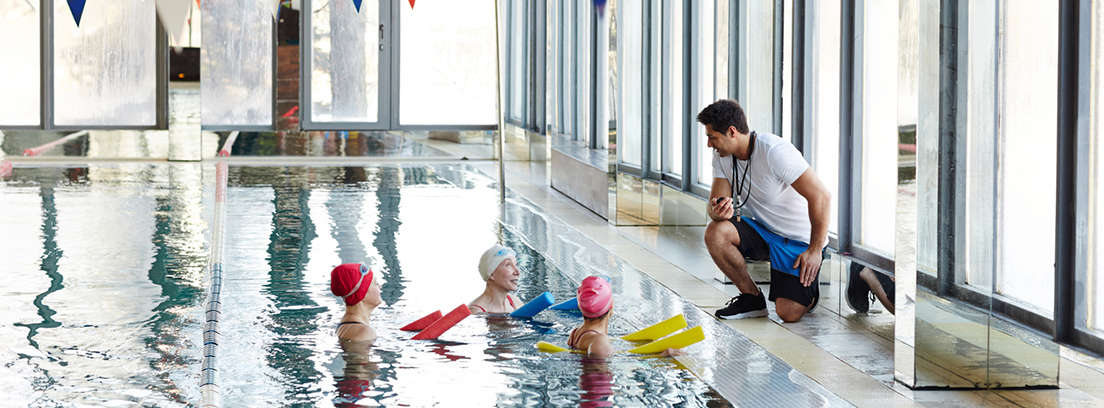 Hombre y mujer mayores sonrientes, haciendo ejercicio en el gimnasio, con pesas en las manos y sentados sobre pelotas hinchables